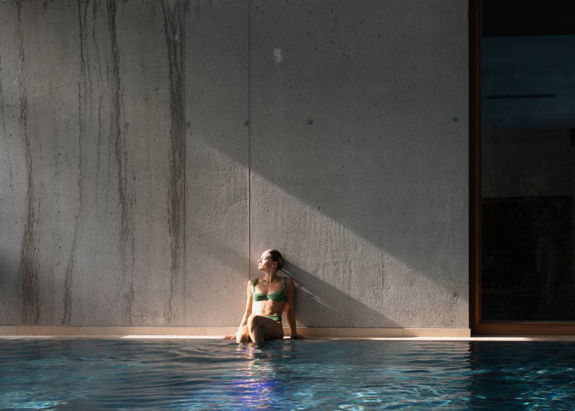 Frau sitzt am Indoorpool des Hotels Das Kronthaler