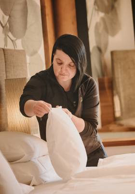 Housekeeping Mitarbeiterin schüttelt ein Kissen auf