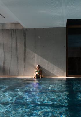 Frau sitzt am Indoorpool des Hotels Das Kronthaler