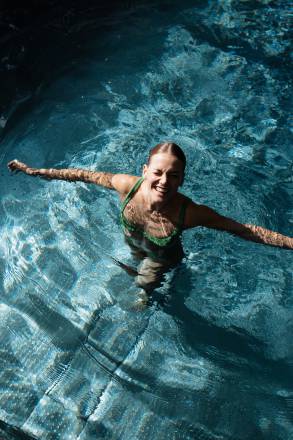 Frau im Pool grinst in die Kamera 