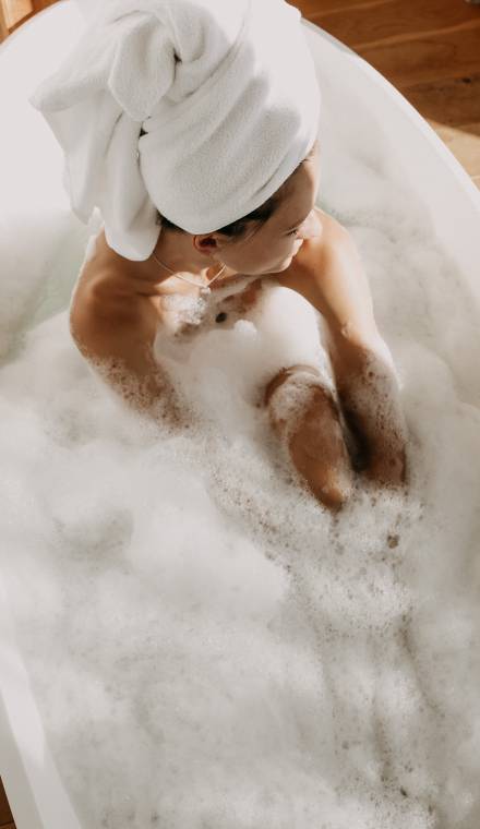Frau sitzt in einer Badewanne mit viel Schaum