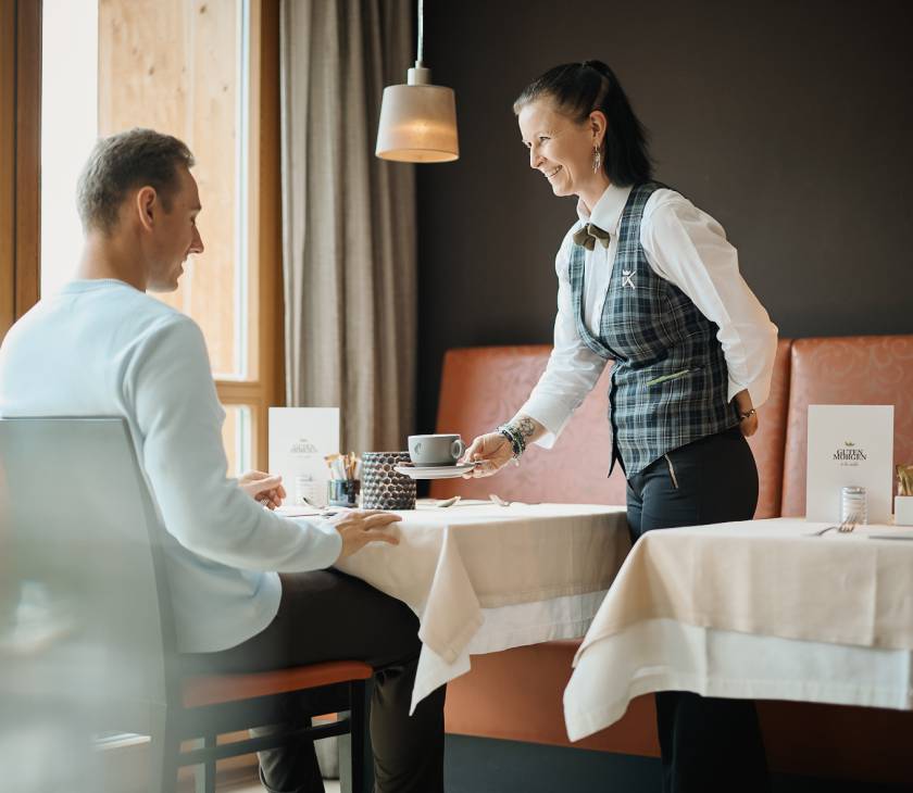 Service Mitarbeiterin serviert einem Gast einen Kaffee